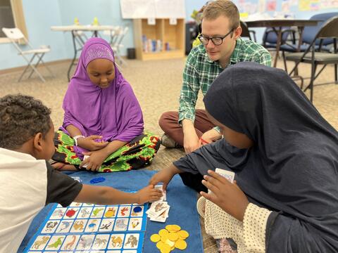 Three students play a game with a teacher.