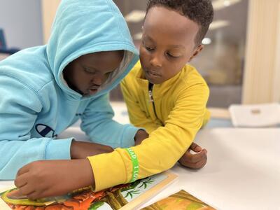 Two boys in colorful sweatshirts work together on a puzzle.